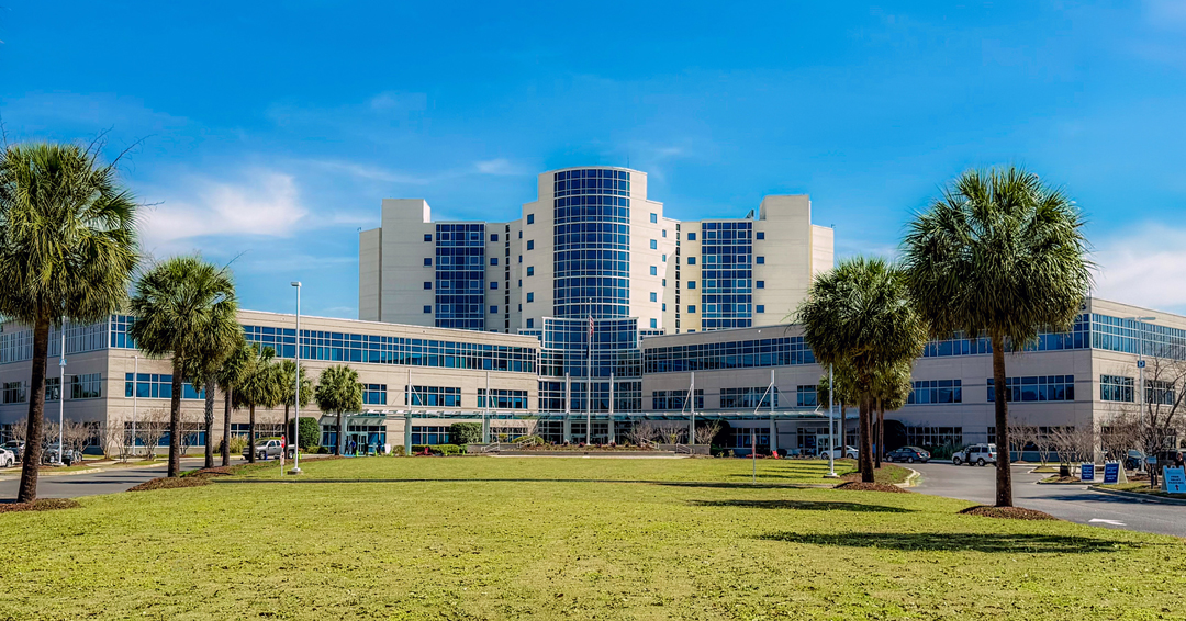 MUSC Florence Medical Center's central glass tower, front lawn and palm-lined approach.