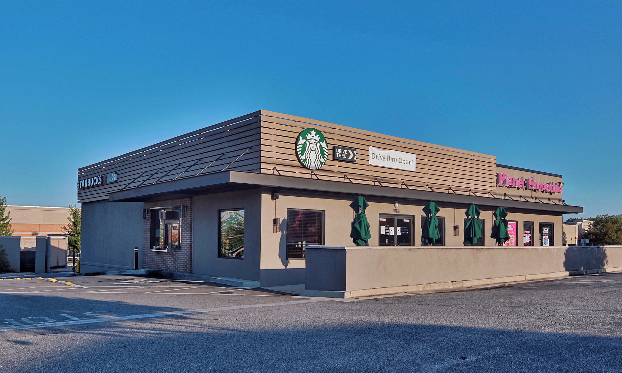 Starbucks in Athens with a walled patio, green umbrellas and drive-through signage.