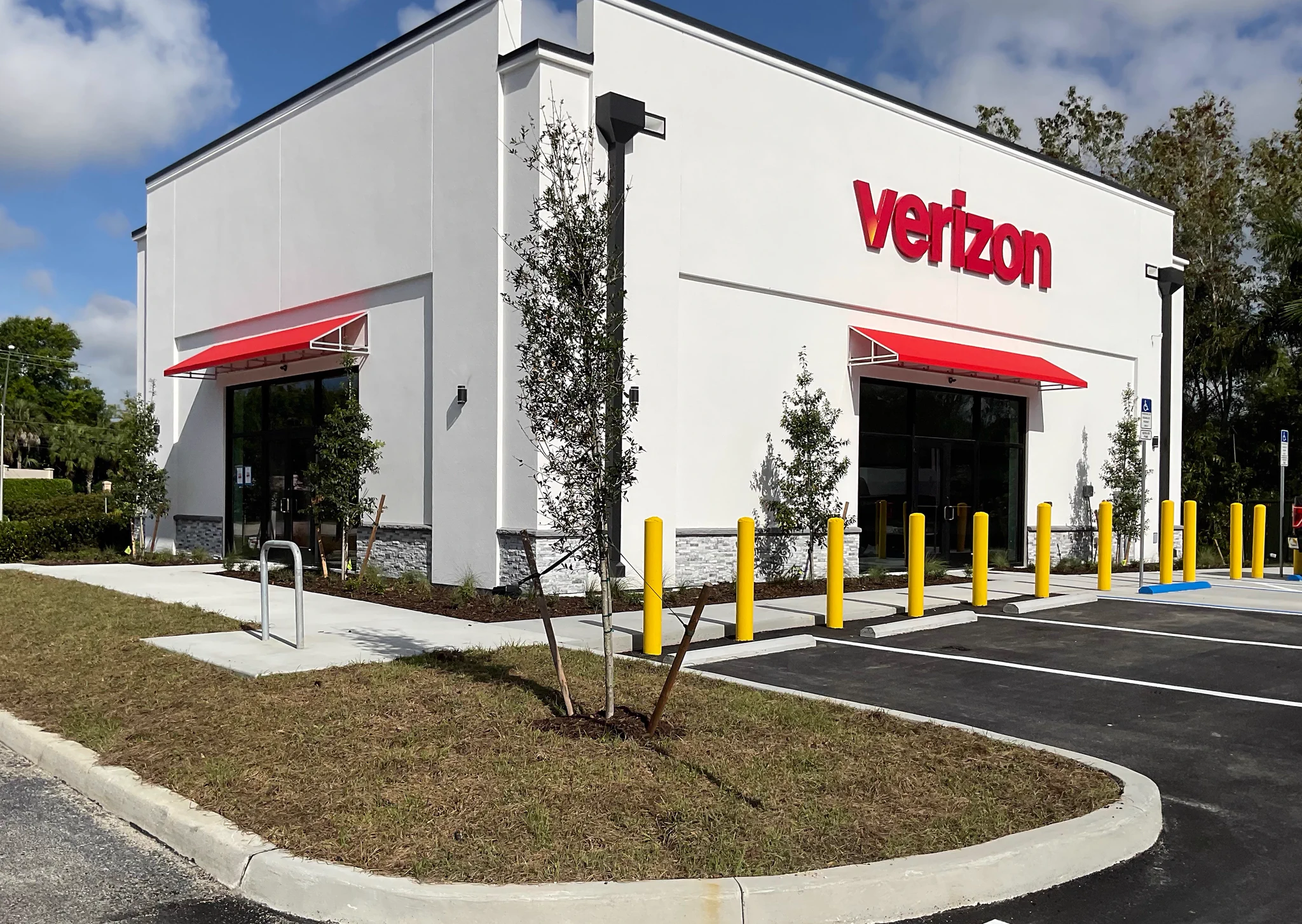 Verizon storefront with red awnings and landscaped parking area in Naples, FL.
