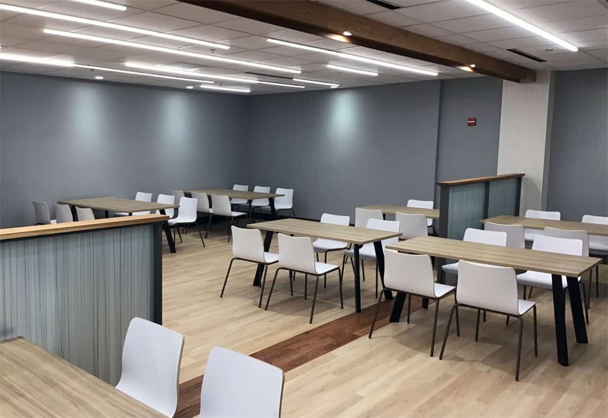 Dining tables and white chairs beside a frosted-glass partition in the Grand Cafe.