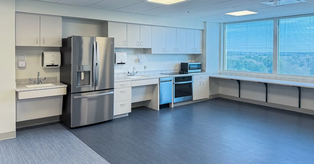 Window-side kitchenette with white cabinetry and a long counter at MUSC in Florence.