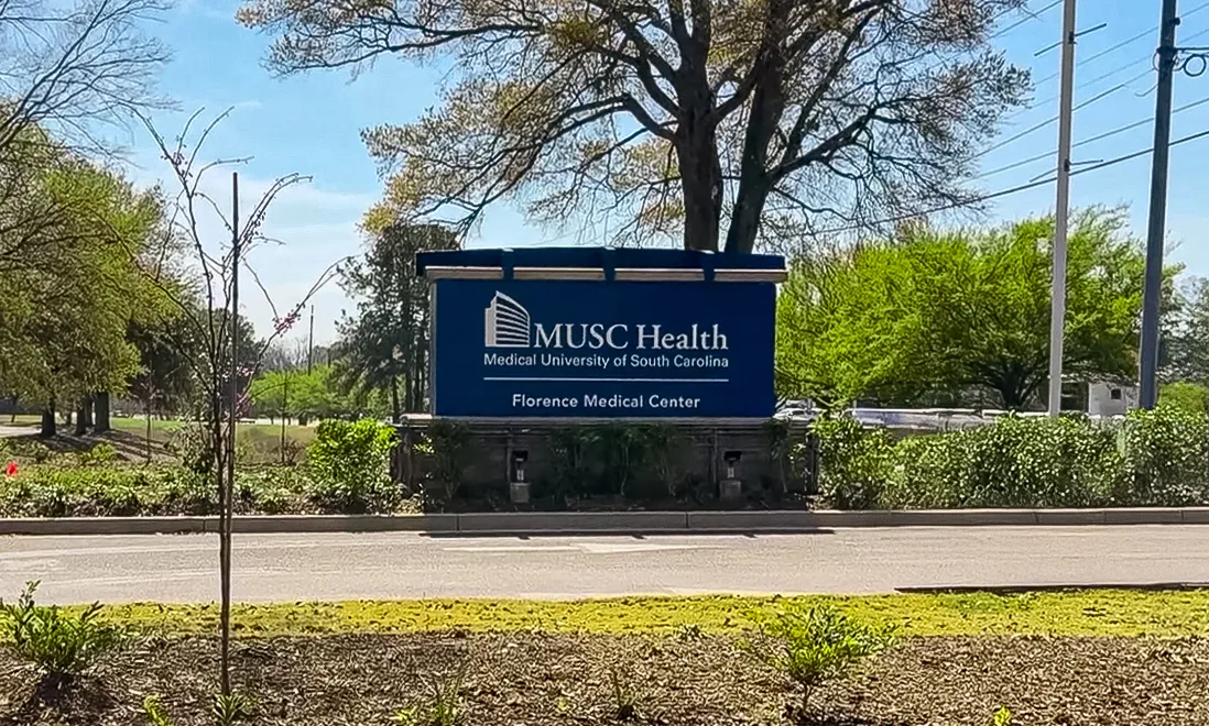 Roadside view of the MUSC Health Florence Medical Center sign and surrounding trees.