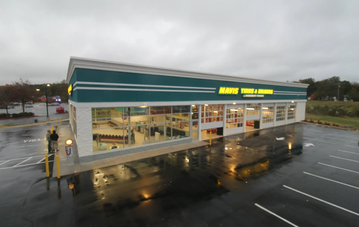 Mavis Tires & Brakes in Thomasville, NC, with its glass-fronted customer area and service bays lit at dusk.