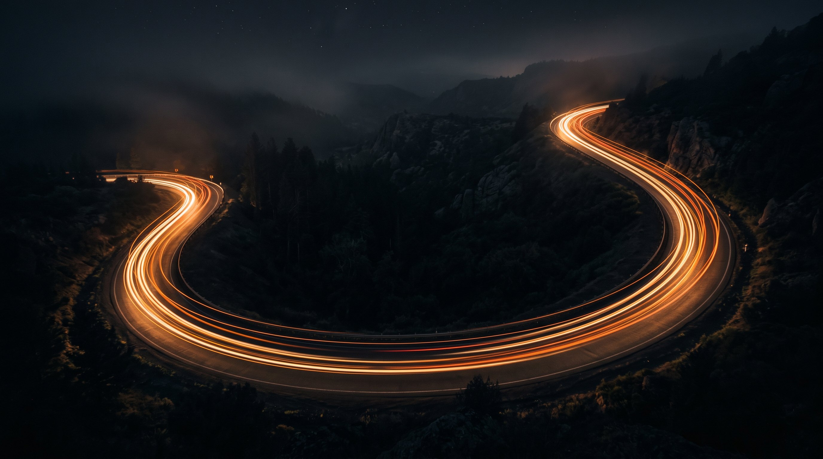 Amber light trails streaking down a dark highway toward the horizon.