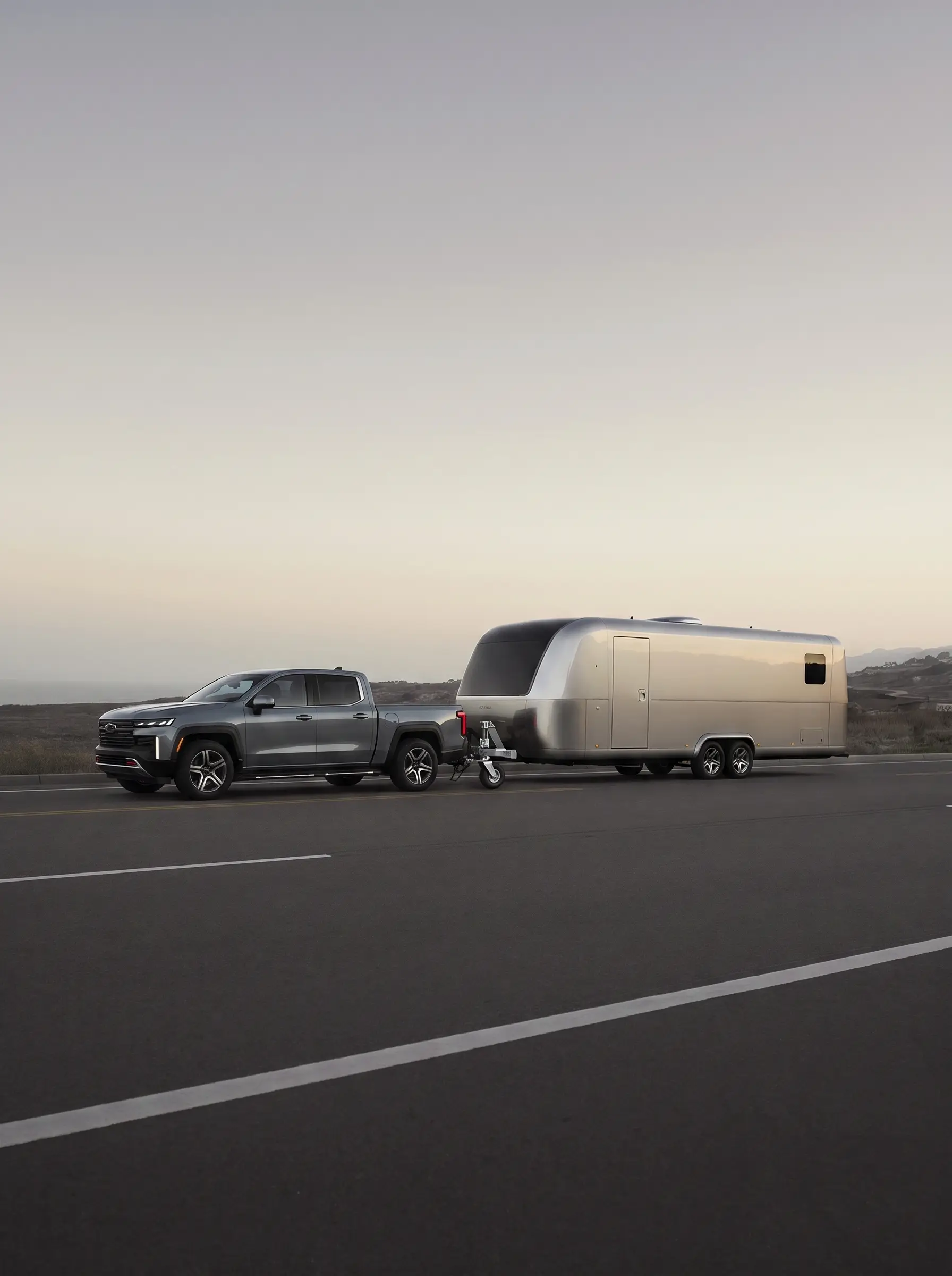 TowEra V1 test rig: pickup towing a silver trailer with the front caster assembly under the trailer tongue, dusk highway