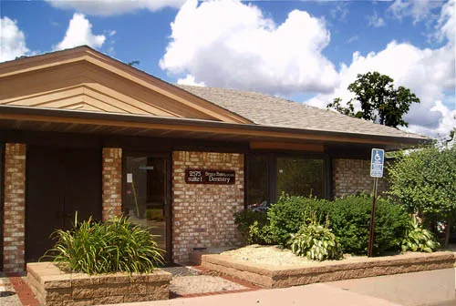 Exterior view of the Bates Dental Care building, featuring brick architecture, landscaped greenery, and a visible dental office sign.