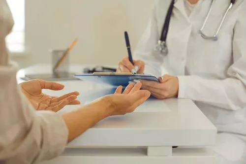 Close-up of a doctor writing on a clipboard while consulting a patient, symbolizing treatment planning or dental case documentation.
