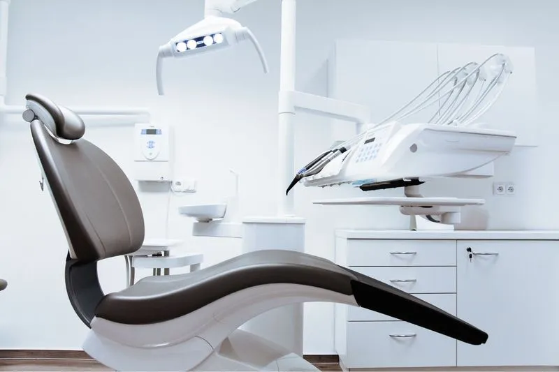 A sleek, ergonomic dental chair in a bright, clean clinic equipped with overhead lighting and advanced dental instruments.
