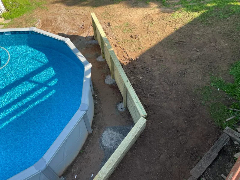 Wooden retaining wall built around above-ground pool.