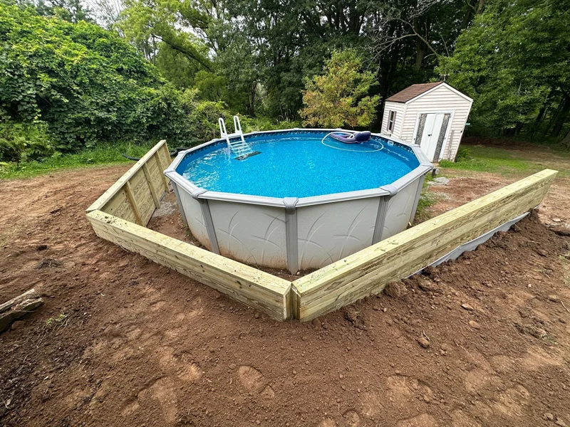 Wooden retaining wall built around above-ground pool.