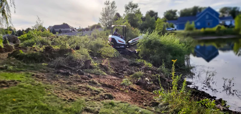 Clearing of riverside terrain with an excavator.