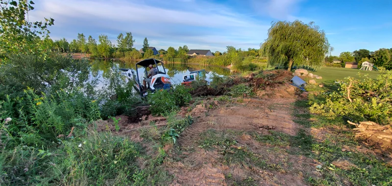 Clearing of riverside terrain with an excavator.