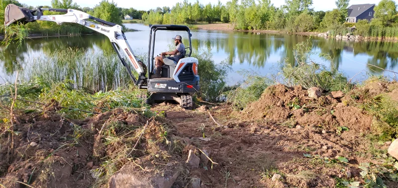 Clearing of riverside terrain with an excavator.