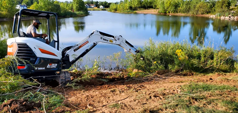 Clearing of riverside terrain with an excavator.