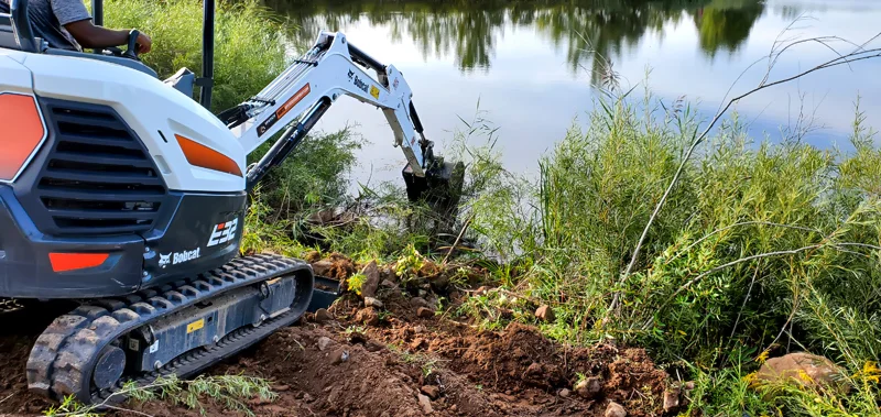 Clearing of riverside terrain with an excavator.