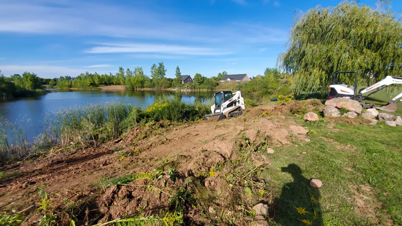 Clearing of riverside terrain with an excavator.