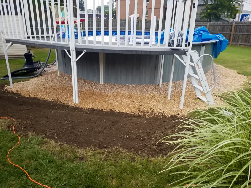 Poolside landscaping with gravel, pebbles, and prepared soil.