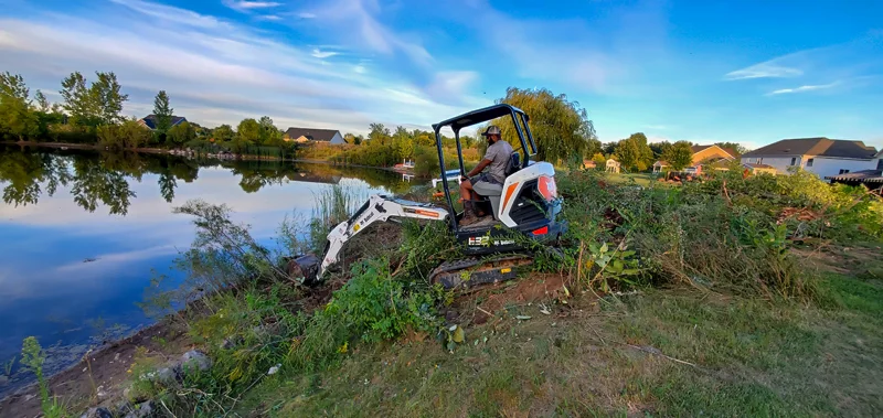Clearing of riverside terrain with an excavator.