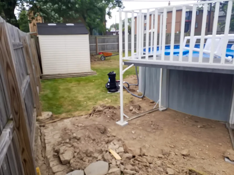 Poolside landscaping with gravel, pebbles, and prepared soil.