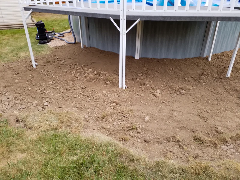 Poolside landscaping with gravel, pebbles, and prepared soil.
