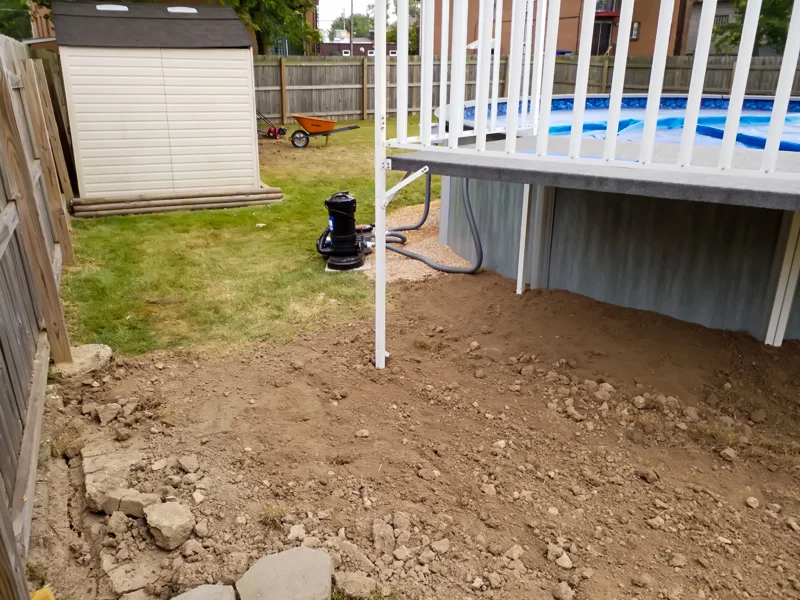 Poolside landscaping with gravel, pebbles, and prepared soil.