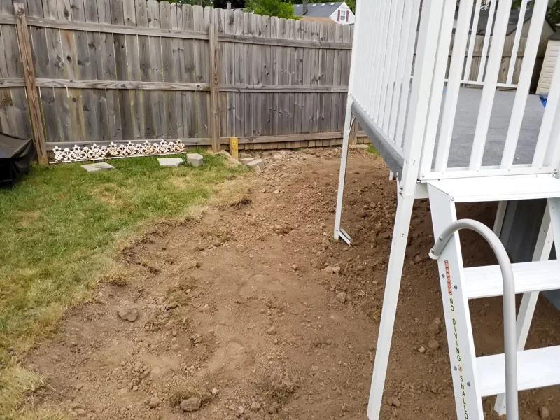 Poolside landscaping with gravel, pebbles, and prepared soil.