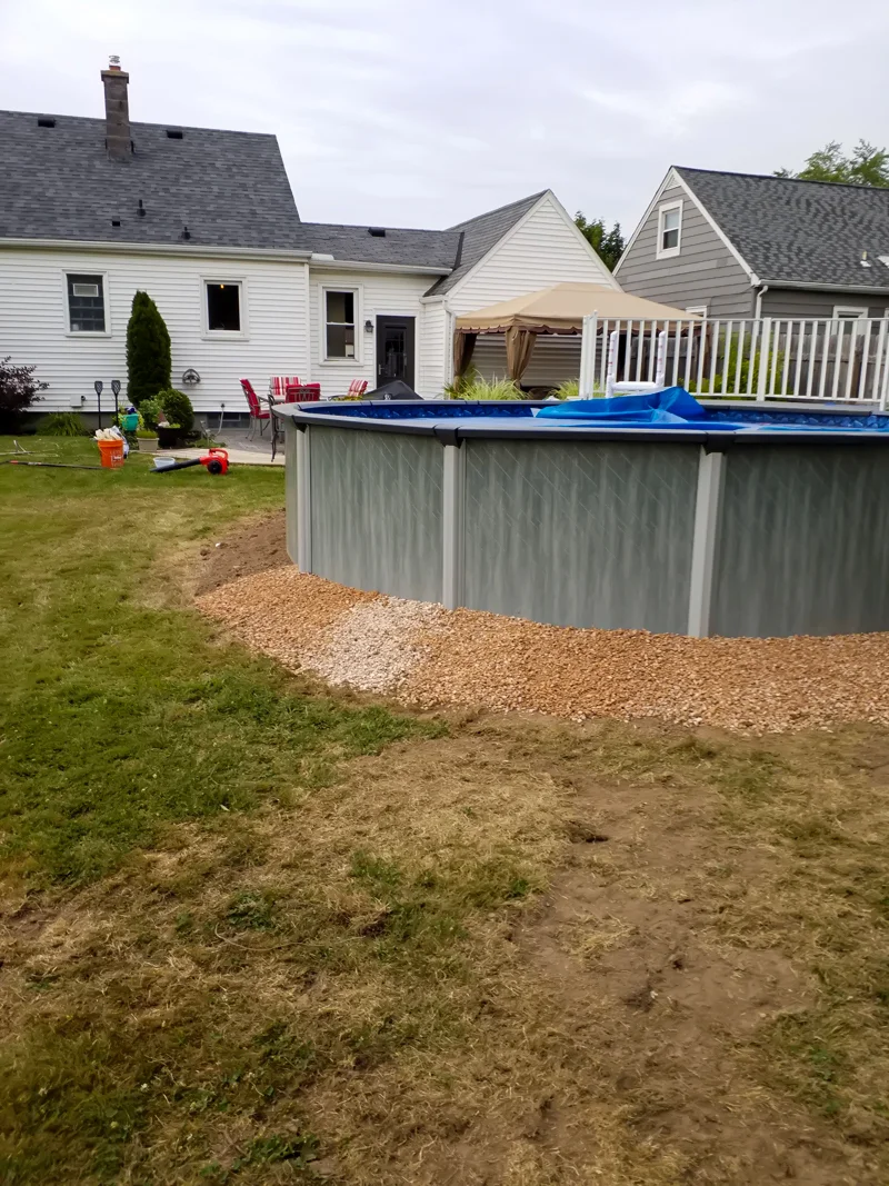 Poolside landscaping with gravel, pebbles, and prepared soil.