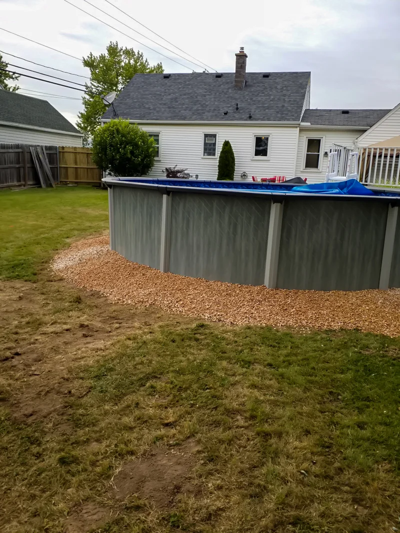Poolside landscaping with gravel, pebbles, and prepared soil.