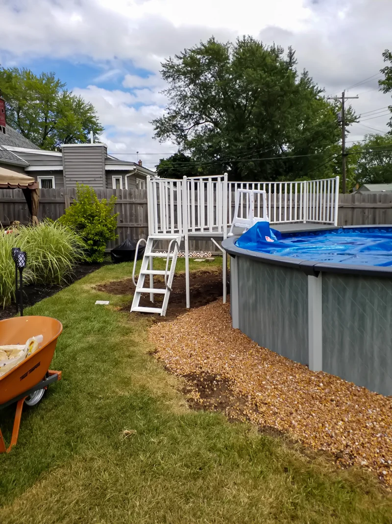 Poolside landscaping with gravel, pebbles, and prepared soil.