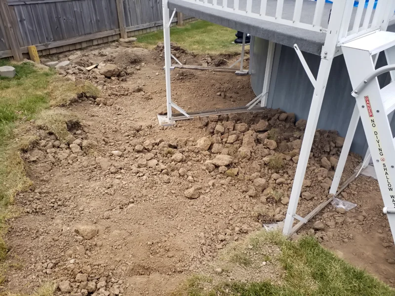 Poolside landscaping with gravel, pebbles, and prepared soil.