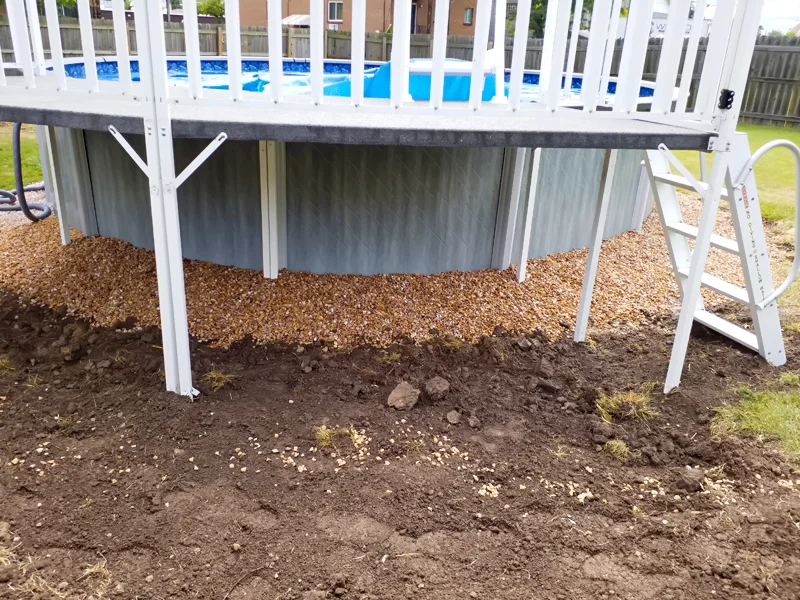 Poolside landscaping with gravel, pebbles, and prepared soil.