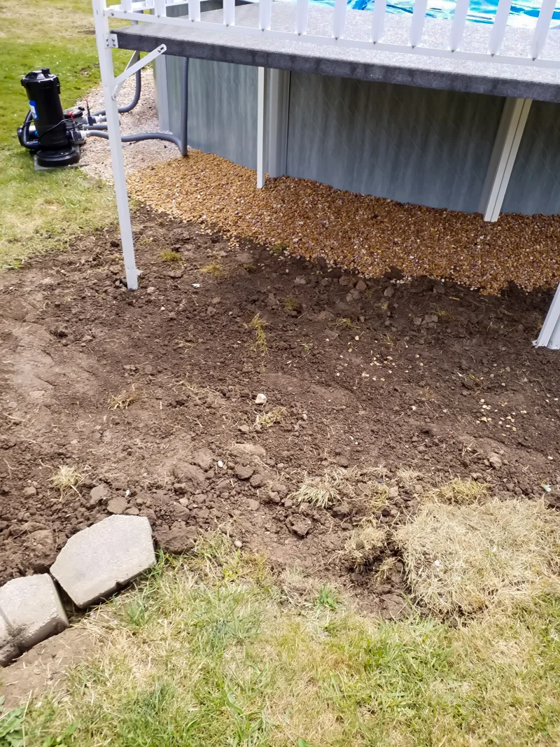 Poolside landscaping with gravel, pebbles, and prepared soil.