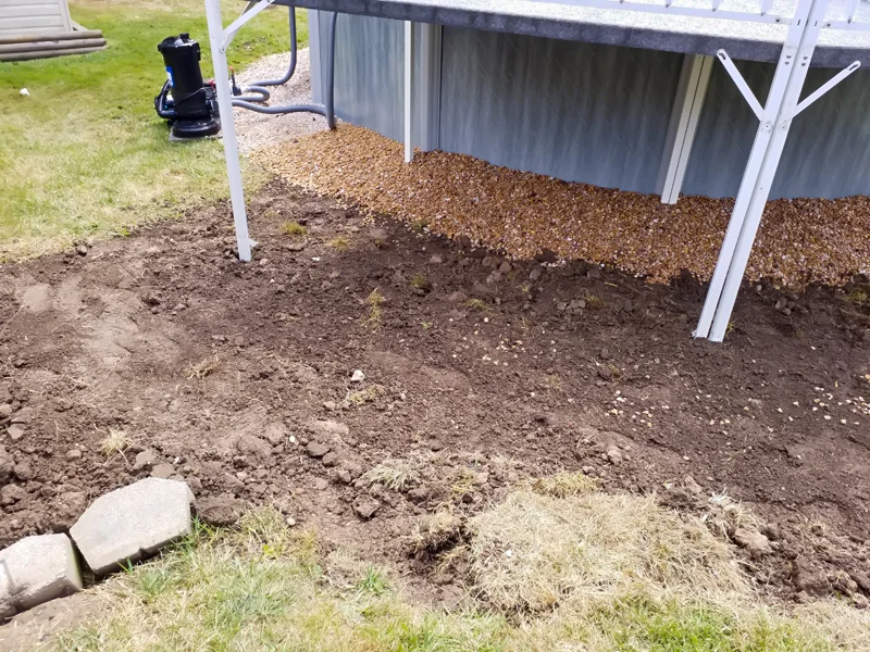 Poolside landscaping with gravel, pebbles, and prepared soil.