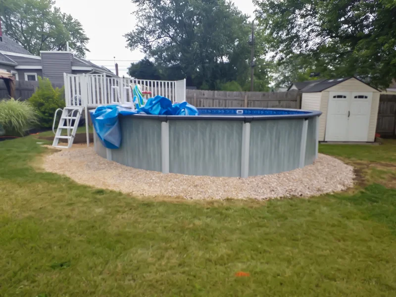 Poolside landscaping with gravel, pebbles, and prepared soil.