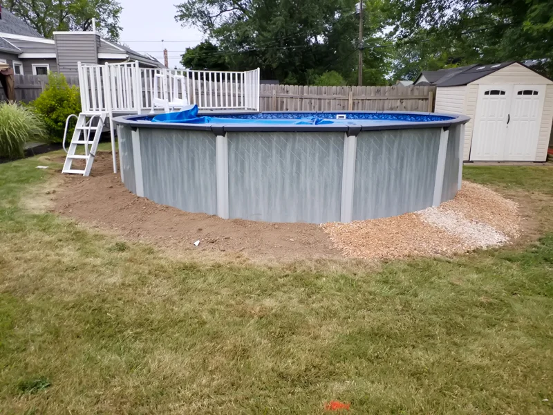 Poolside landscaping with gravel, pebbles, and prepared soil.