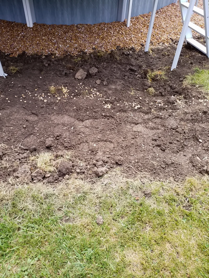 Poolside landscaping with gravel, pebbles, and prepared soil.