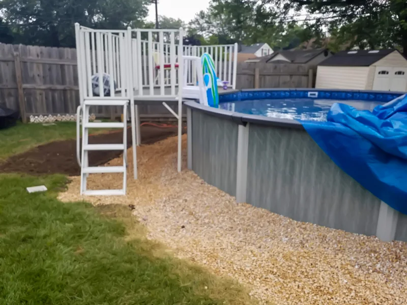 Poolside landscaping with gravel, pebbles, and prepared soil.