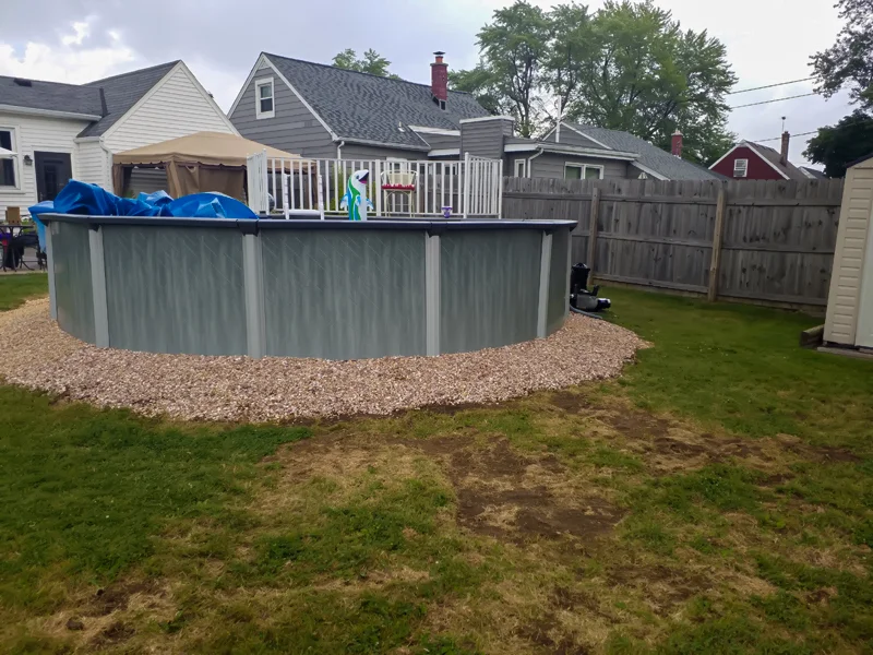 Poolside landscaping with gravel, pebbles, and prepared soil.