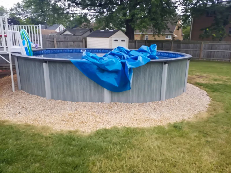 Poolside landscaping with gravel, pebbles, and prepared soil.