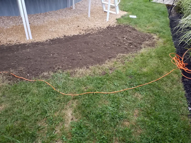 Poolside landscaping with gravel, pebbles, and prepared soil.