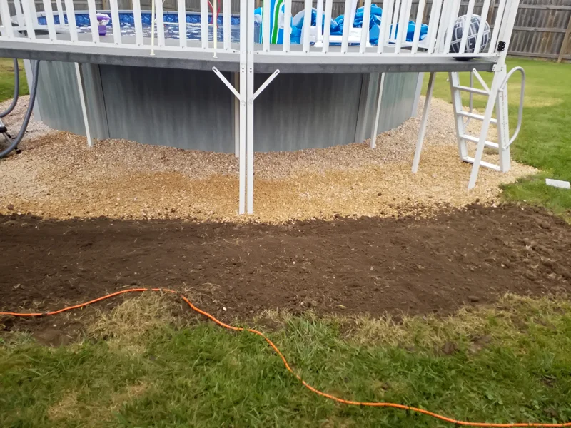 Poolside landscaping with gravel, pebbles, and prepared soil.