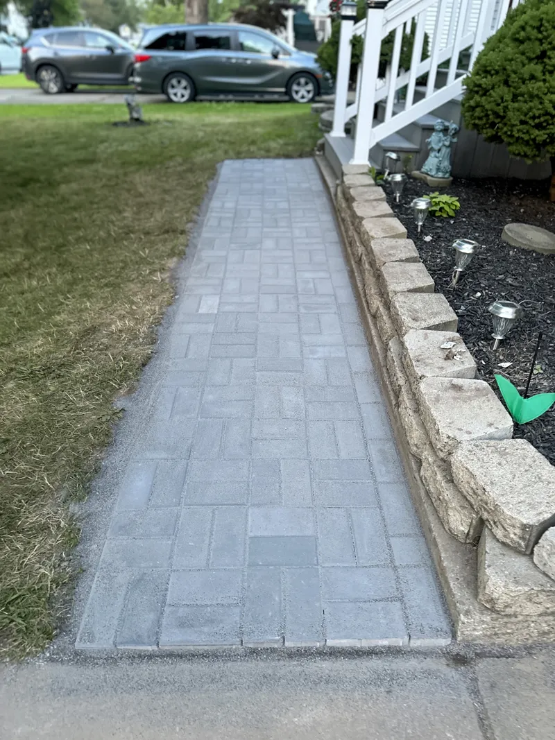 Close-up of newly installed brick pathway beside a stone garden border.