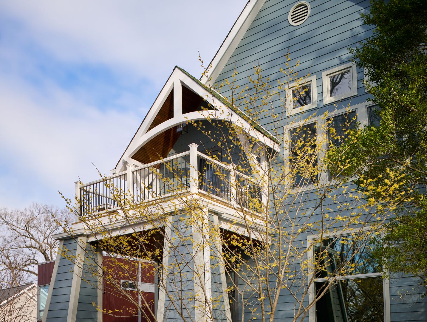 Front view of renovated Bethesda home showcasing new siding with lush landscaping and trees in the foreground