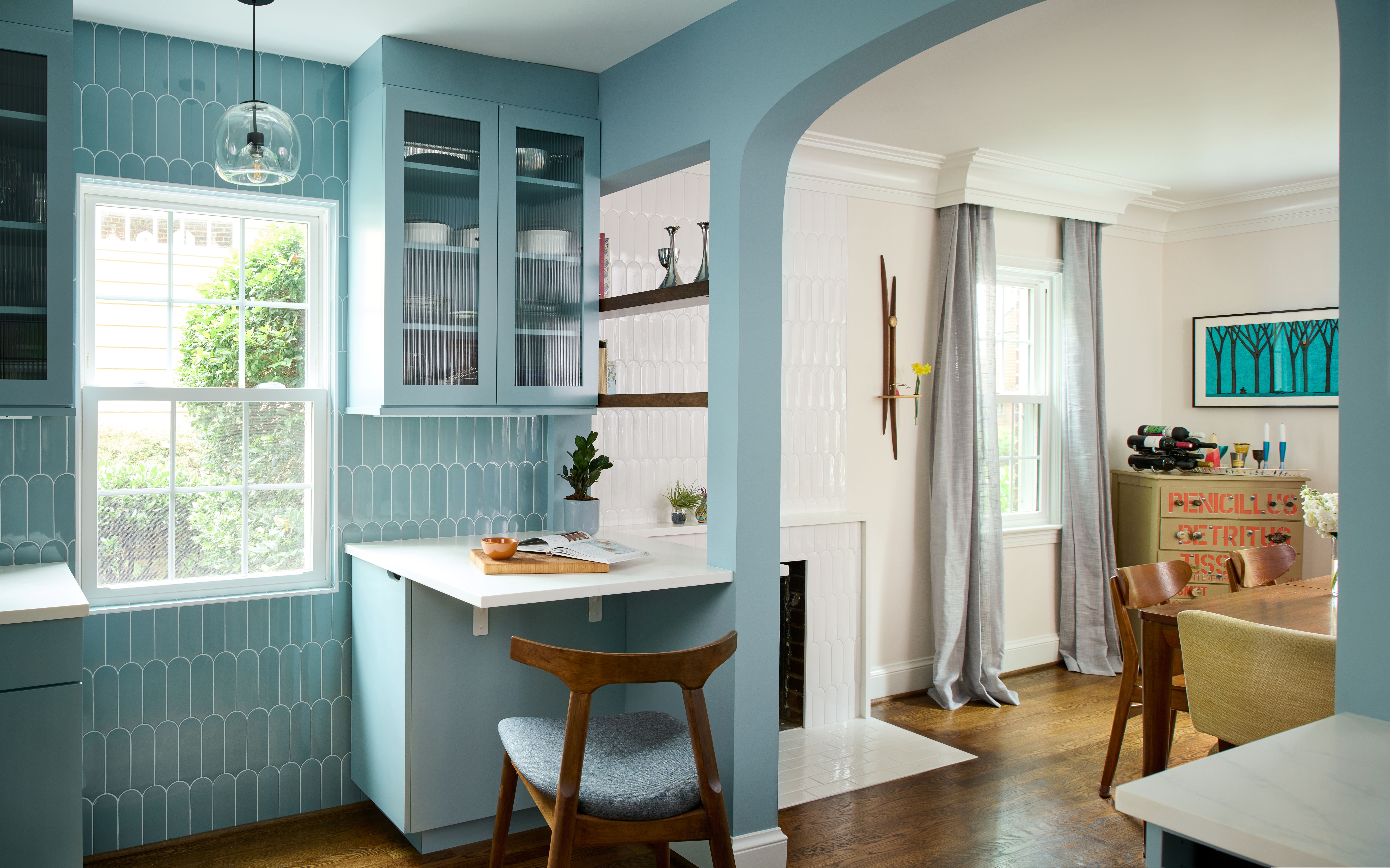 Elegant blue kitchen renovation featuring glass-front cabinets, modern lighting, and open design