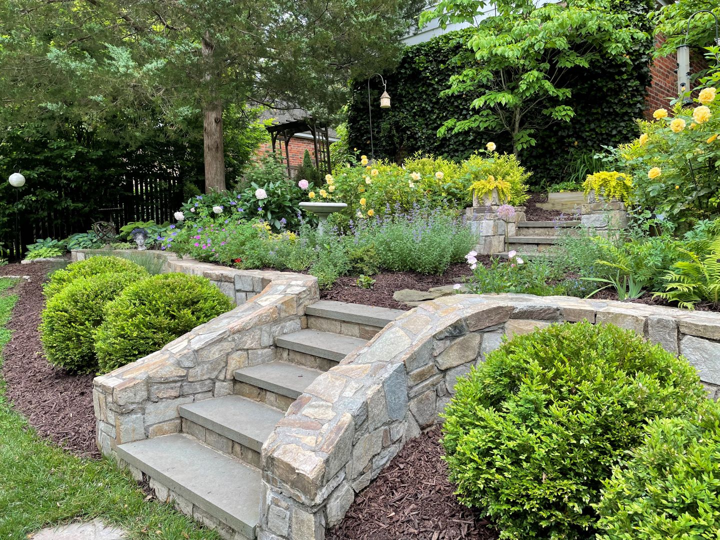 Transformed hillside landscape with integrated terracing, native plantings, and natural stone elements