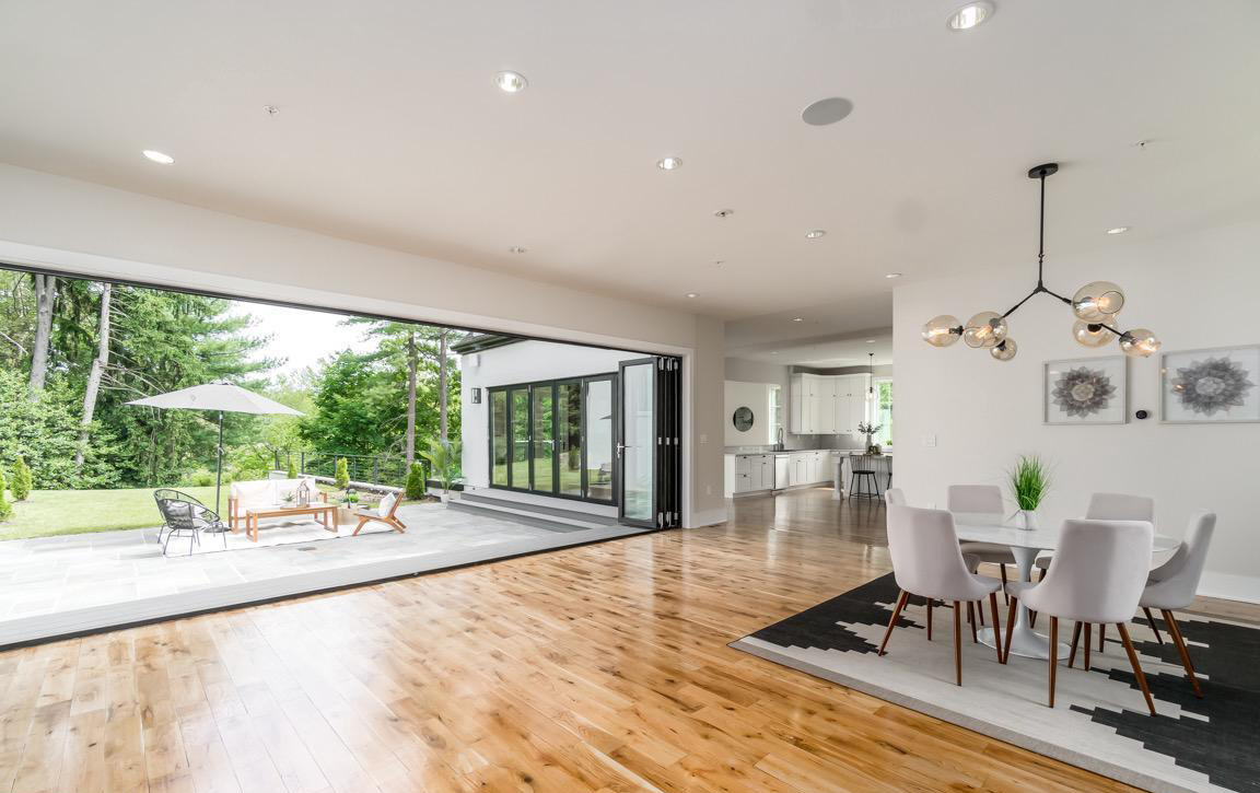 Contemporary dining area with designer lighting fixture, integrated storage, and connection to outdoor living space