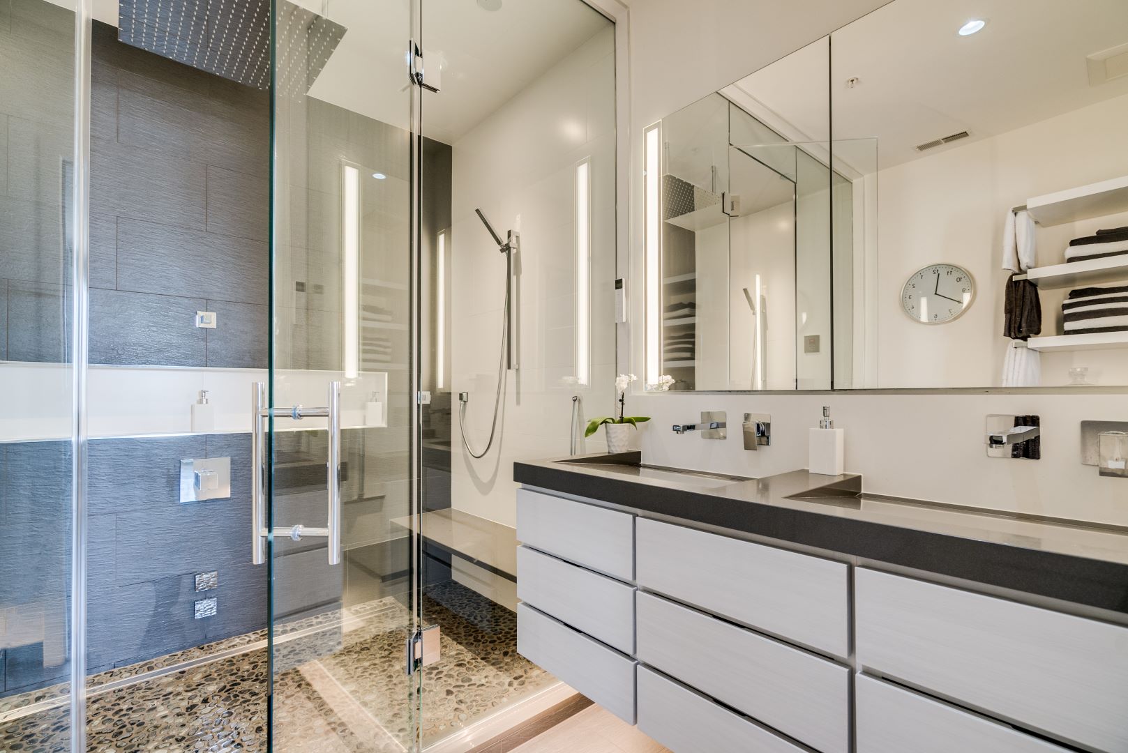 Sleek walk-in shower with glass enclosure, rainfall showerhead, and designer tile in urban loft bathroom