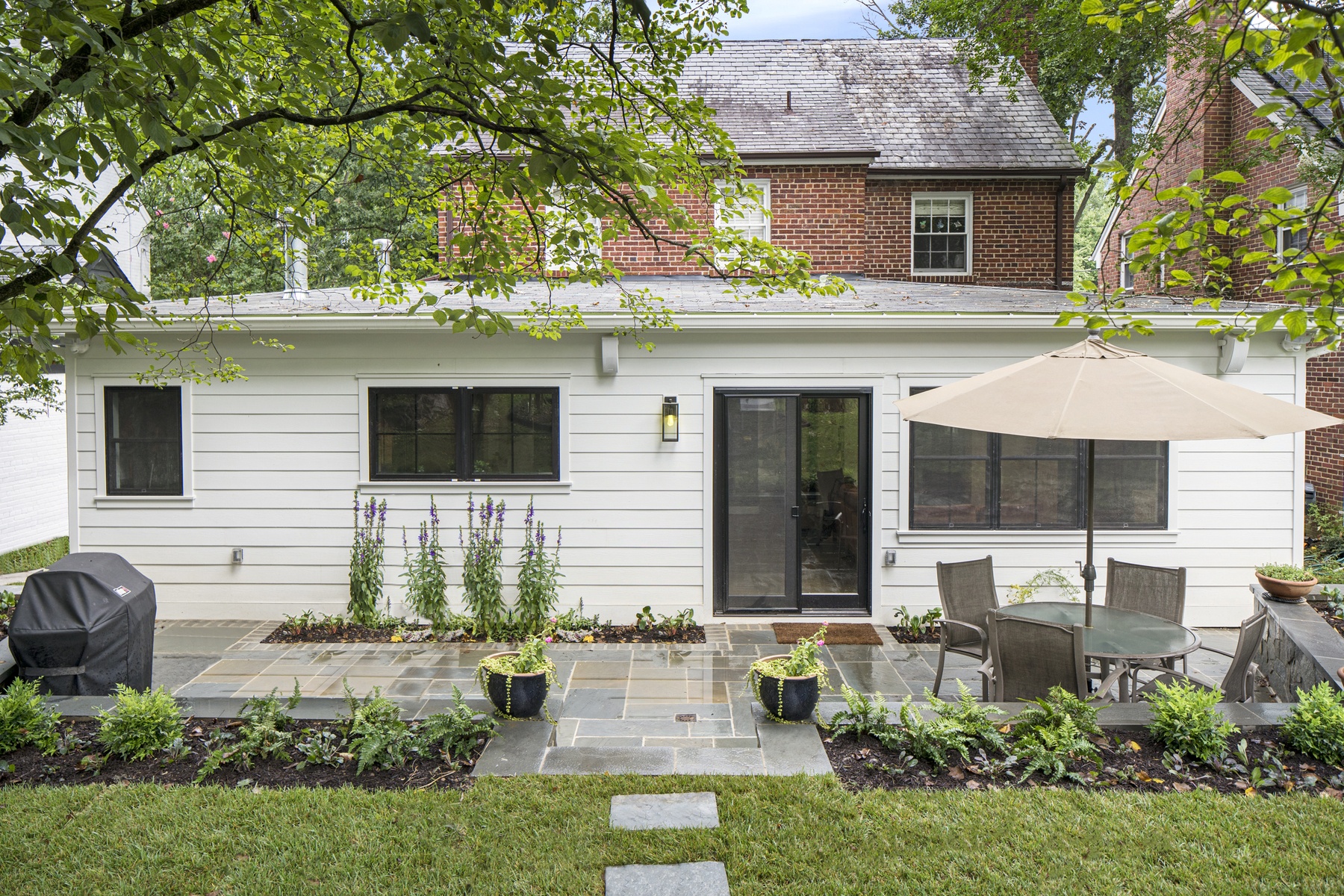 Side angle of renovated exterior showcasing architectural details, material selection, and landscaping elements