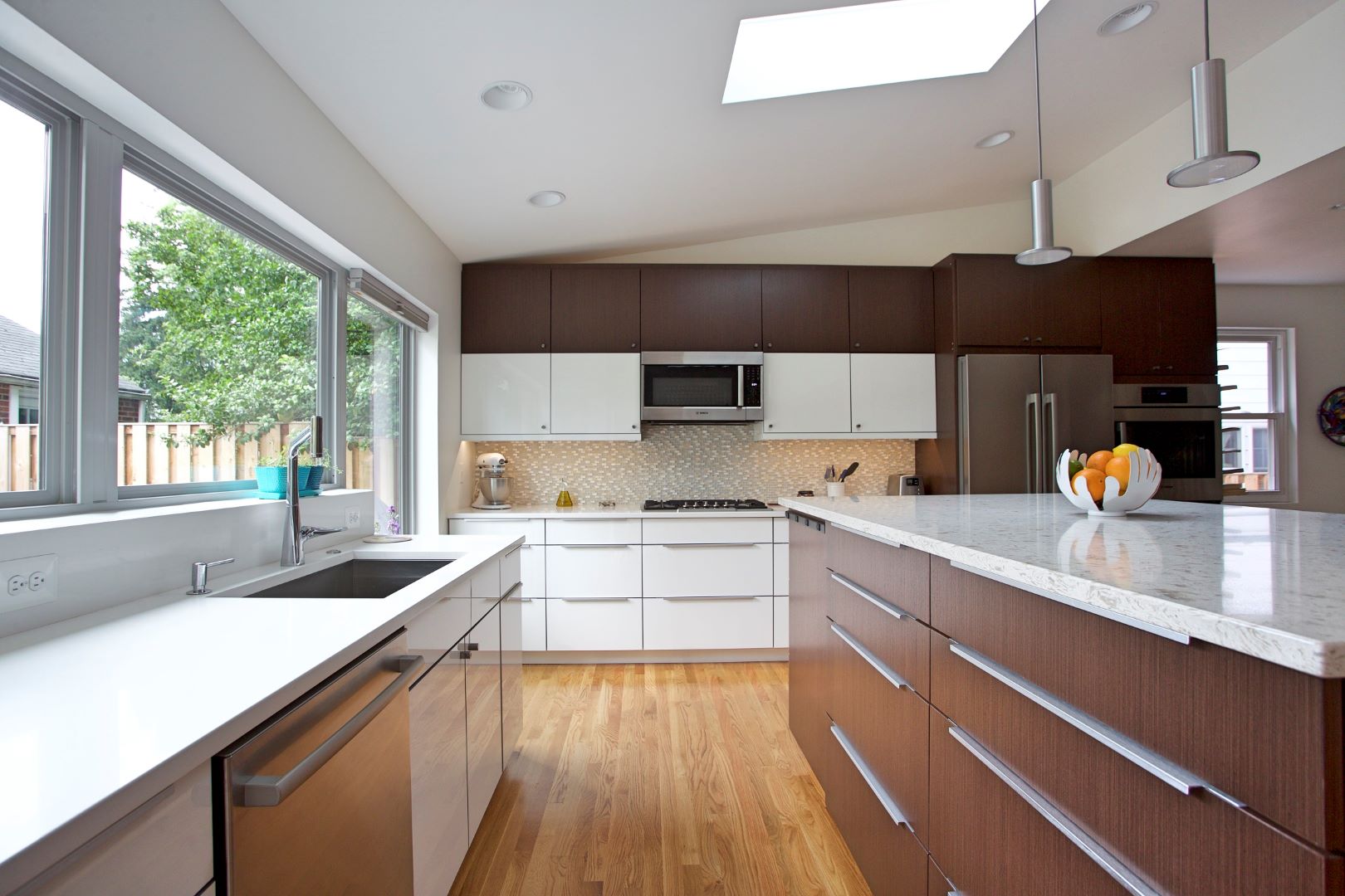 Open concept kitchen with central island, modern cabinetry, and distinctive orange accent wall in Mid-Century inspired space