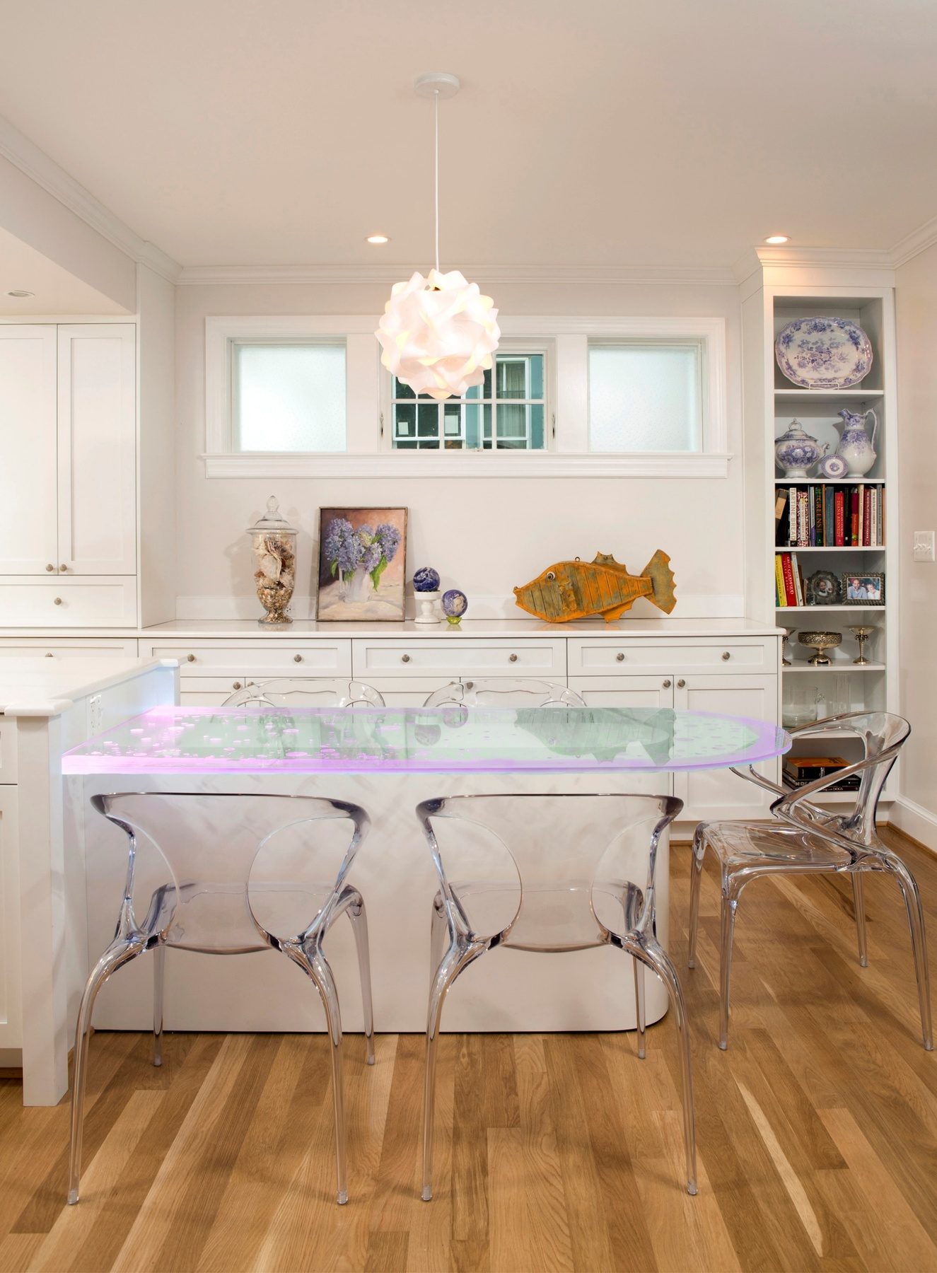 Custom glass breakfast table with RGB color-changing LED lighting attached to kitchen island creating vibrant ambiance